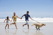 Family with dog running on beach