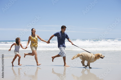 Photo: Family with dog running on beach Family with dog running on beach