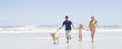 Family with dog running on beach