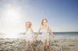 Twin girls holding hands on beach