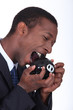 Man trying to bite open a piggy bank