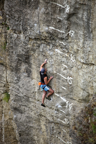 Photo: Rock climber on cliff battling his way up Rock climber on cliff battling his way up