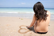 woman draws a heart in the sand