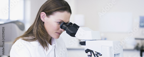 Photo: Scientist looking through microscope in laboratory Scientist looking through microscope in laboratory