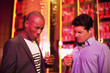 Men with shot glasses making a face in nightclub