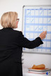 Mature businesswoman writing on a wall planner