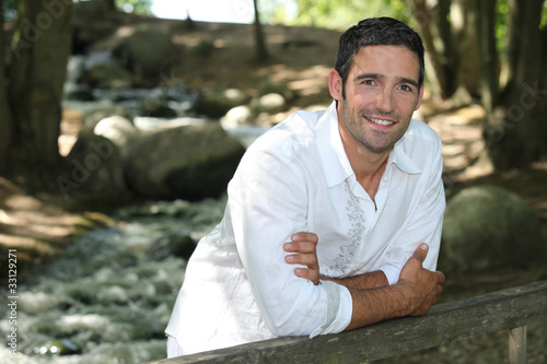 Photo: Man standing by a woodland stream Man standing by a woodland stream
