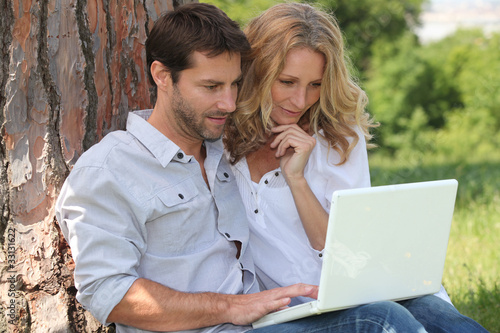 Photo: Couple in park on laptop computer Couple in park on laptop computer