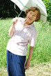 Foto: Fröhliche Seniorin mit Sonnenschirm im Grünen Fröhliche Seniorin mit Sonnenschirm im Grünen