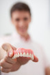 Man in dentist's office holding false teeth