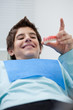 Boy in dentist's chair holding false teeth