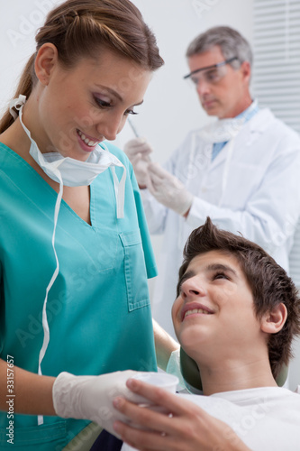 Photo: Dentist's assistant giving boy in chair beaker Dentist's assistant giving boy in chair beaker