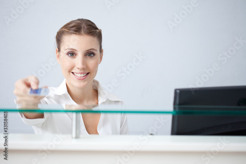 Photo: Smiling receptionist holding health insurance card Smiling receptionist holding health insurance card