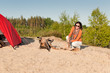 Camping happy woman sitting by campfire on beach Camping happy woman sitting by campfire on beach