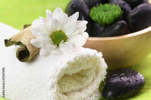 Photo: Spa, flower on the towel, and a bowl with black stones Spa, flower on the towel, and a bowl with black stones