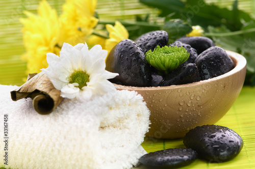 Photo: Spa, flower on the towel, and a bowl with black stones Spa, flower on the towel, and a bowl with black stones