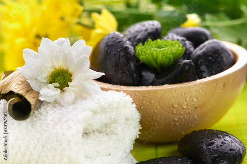 Photo: Spa, flower on the towel, and a bowl with black stones Spa, flower on the towel, and a bowl with black stones