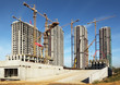 Four tall buildings under construction with cranes against sky