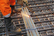Worker legs in orange clothes weld metal grating