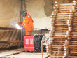 Worker in orange clothes weld metal gratings