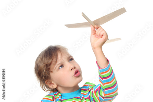 Foto: little girl in striped shirt playing with wooden toy plane little girl in striped shirt playing with wooden toy plane