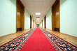 long hallway with brown wood doors, end of corridor, carpet
