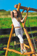 Photo: Cute little girl with blond long hair playing on wooden chain sw Cute little girl with blond long hair playing on wooden chain sw
