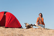 Camping happy woman sitting by campfire on beach