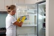 Seniorin putzt Kühlschrank