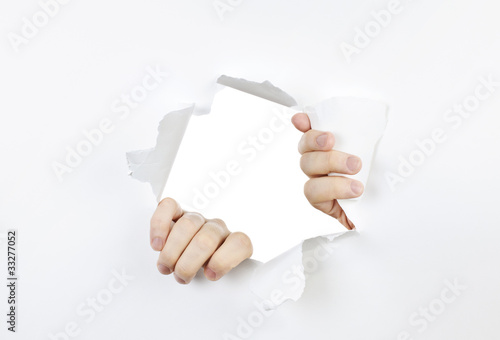 Photo: Hands ripping through hole in paper Hands ripping through hole in paper