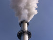 Ein rauchender Industrieschornstein vor strahlend blauem Himmel.