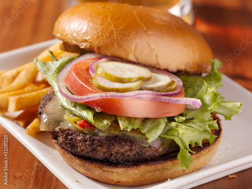 Photo: gourmet cheeseburger with mug of beer in background gourmet cheeseburger with mug of beer in background
