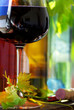 Bottle of red wine with glassand leaves.