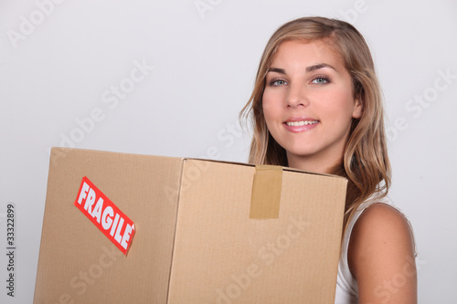 Photo: Young woman with a cardboard box marked FRAGILE Young woman with a cardboard box marked FRAGILE