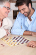 young man playing checkers with older woman