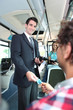 Photo: Smiling conductor checking tickets on a tram Smiling conductor checking tickets on a tram