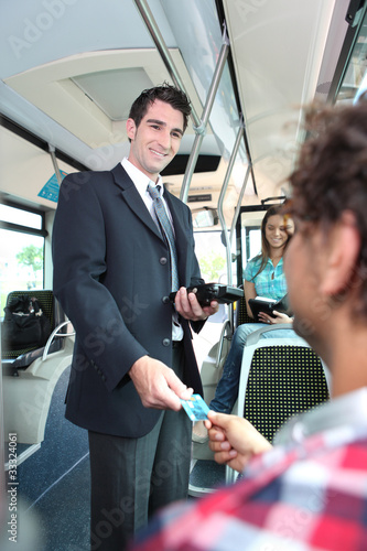 Photo: Smiling conductor checking tickets on a tram Smiling conductor checking tickets on a tram