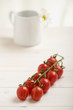 Cherry tomatoes on a white table, white flower in background