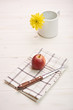 red apple on a white table, in backgroiund a flower