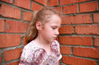 Photo: sad child in front of a brick wall sad child in front of a brick wall