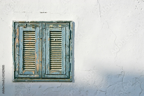 Photo: The old window with blue shutters on a white wall The old window with blue shutters on a white wall
