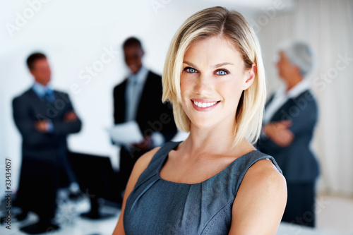 Photo: Female executive with team in background Female executive with team in background