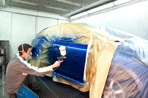Foto: Worker painting a car. Worker painting a car.