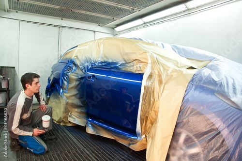 Photo: Worker painting a car. Worker painting a car.