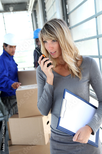 Photo: Businesswoman in warehouse using walkie-talkie Businesswoman in warehouse using walkie-talkie