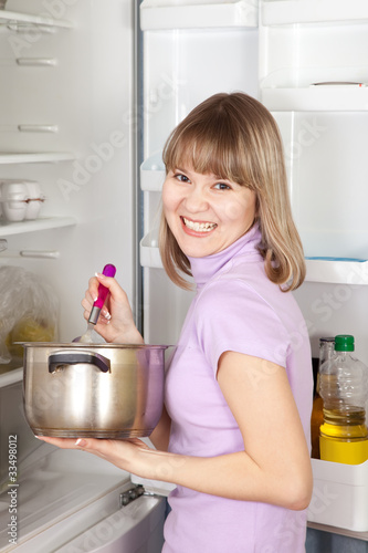 Photo: woman eating from pan near fridge woman eating from pan near fridge