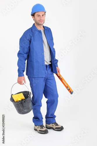 Photo: Builder holding bucket and spirit level. Builder holding bucket and spirit level.