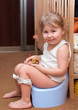 Little girl sitting on a chamber pot in the room