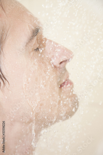 Photo: young adult man fashing face in shower young adult man fashing face in shower