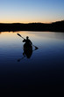 Sillouette of man kayaking on lake